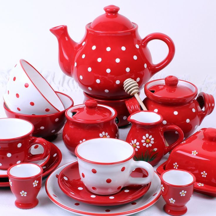 red and white porcelain tea set with polka dot designs on the rims, cups, saucers, and spoons