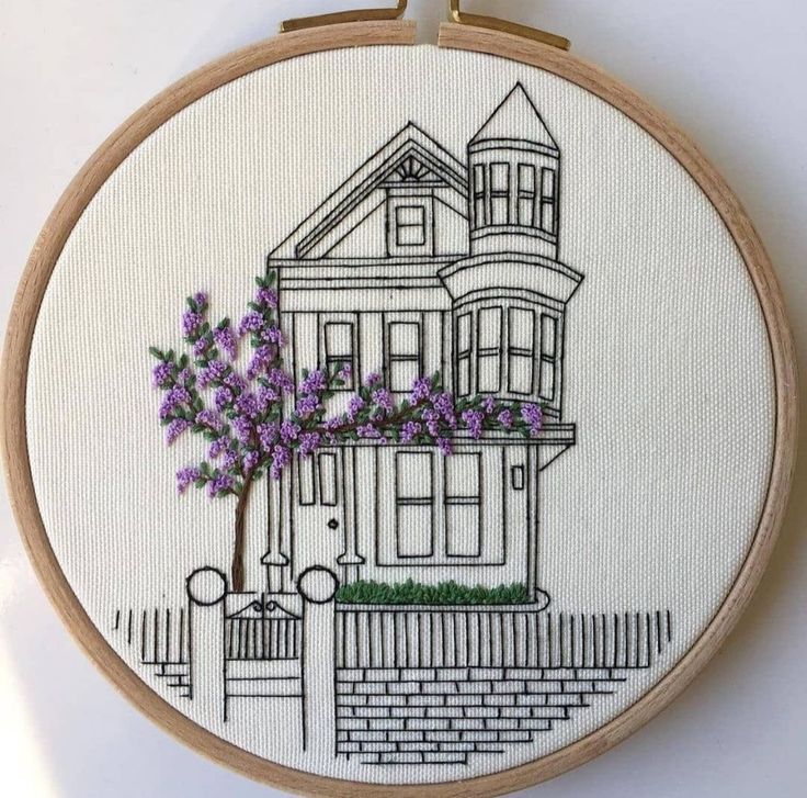 a cross stitch pattern with purple flowers in front of a house