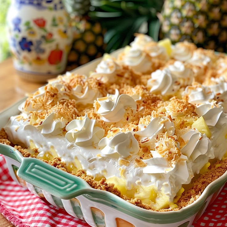 a dessert dish with whipped cream and pineapple toppings on top, sitting on a red checkered tablecloth