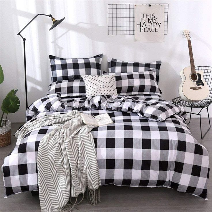 a black and white checkered comforter on a bed in a room with a guitar