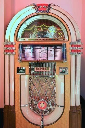 an old fashioned jukebox machine sitting in front of a pink wall