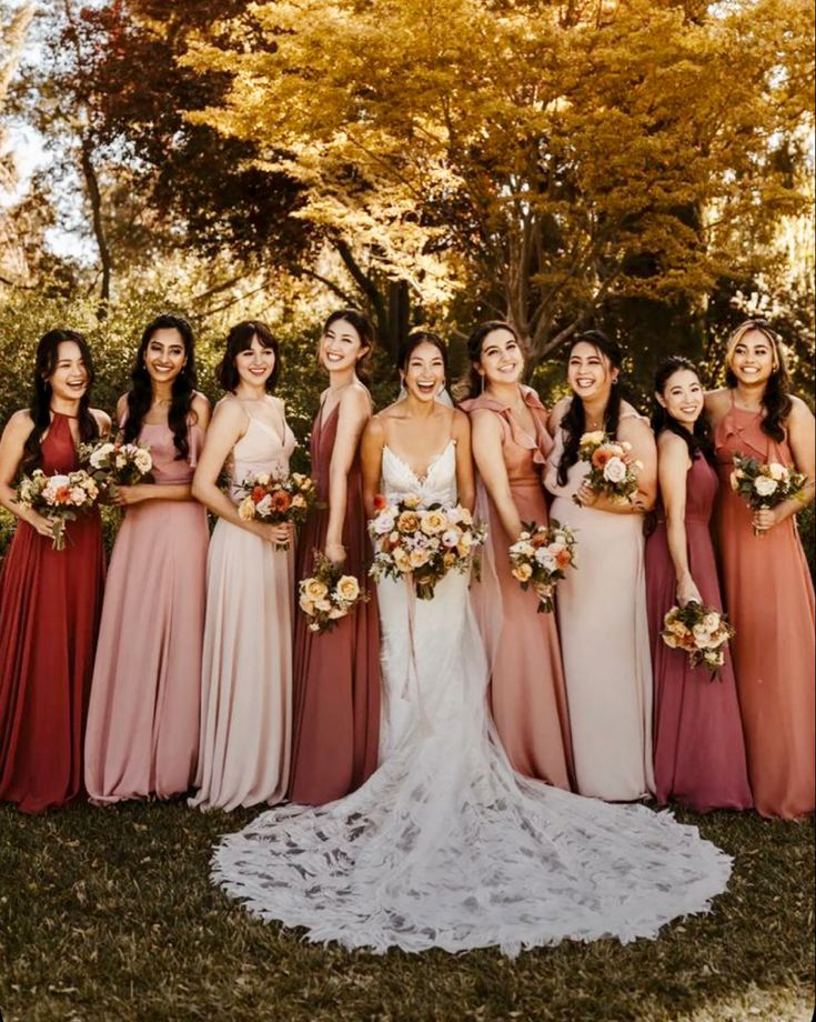 a group of women standing next to each other in front of some trees and grass