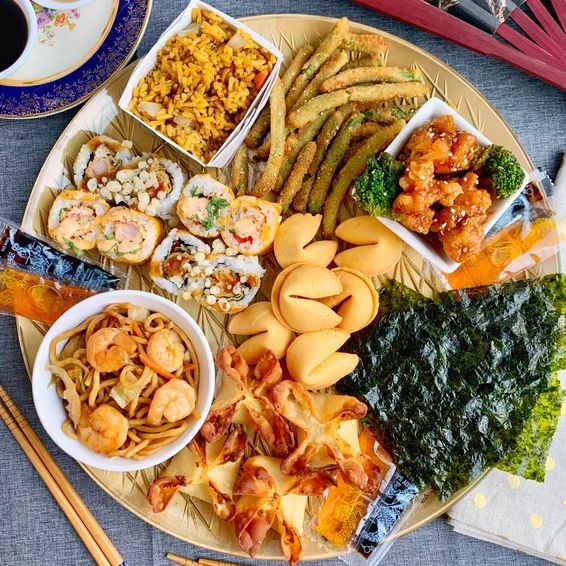 an assortment of food on a plate with chopsticks and saucers next to it