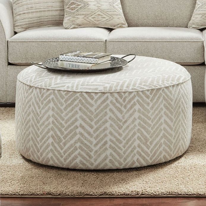 a living room with a couch, chair and ottoman on carpeted floor next to wall