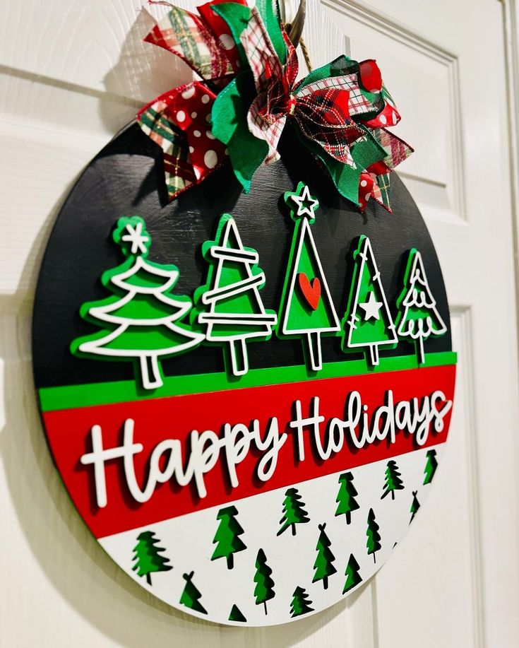 a happy holidays sign hanging on the front door with christmas trees and snowflakes