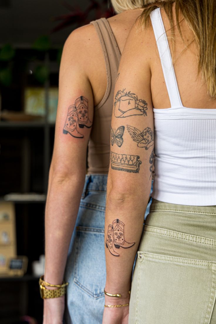 two women standing next to each other with tattoos on their arms