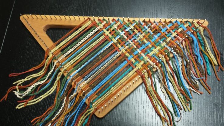 a wooden weaving loom with many different colored yarns