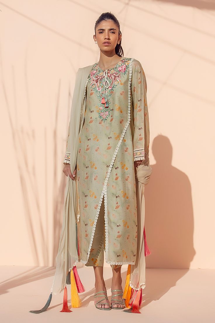 This celadon-colored khaddi silk kurta is printed with embroidered birds and foliage on the neckline that transform this piece into a muted wardrobe work of art. The co-ord printed trousers and colorful tassels hanging from the chiffon dupatta add a playful feel to the piece.