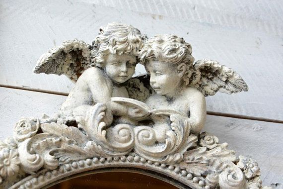 an ornate mirror with two cherubs on it