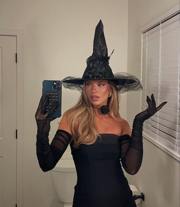 a woman wearing a witches hat and holding a cell phone