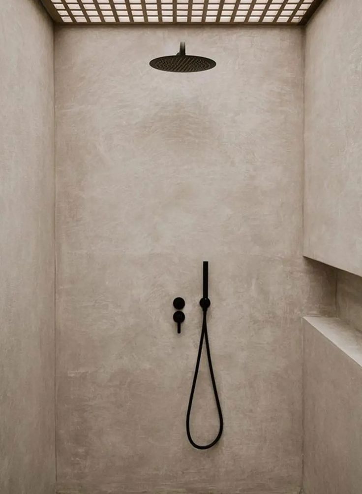 the shower head is mounted to the side of the wall, and it's black faucet