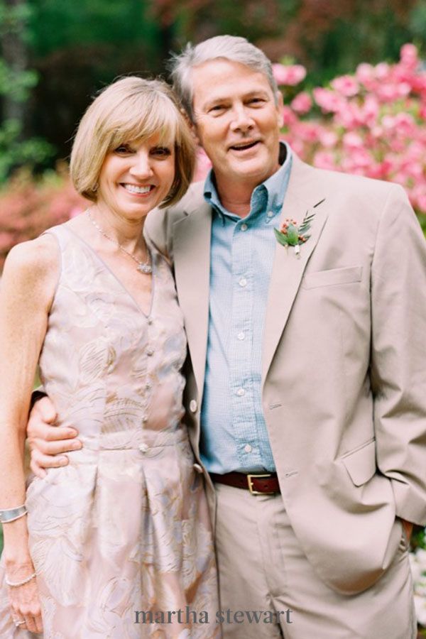 a man and woman standing next to each other in front of flowers