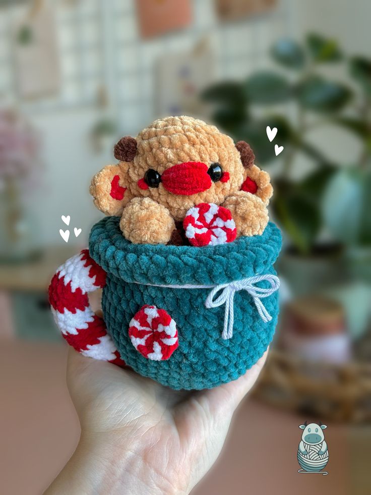 a hand holding a small stuffed animal in a knitted basket with candy canes