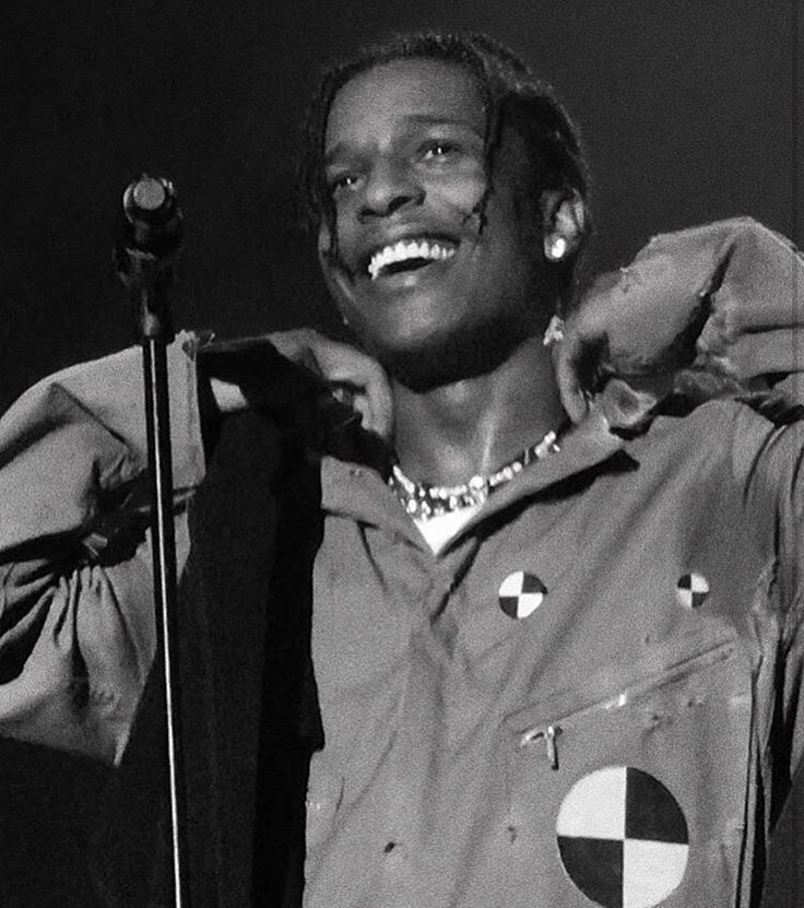 a black and white photo of a smiling man holding a microphone in his right hand