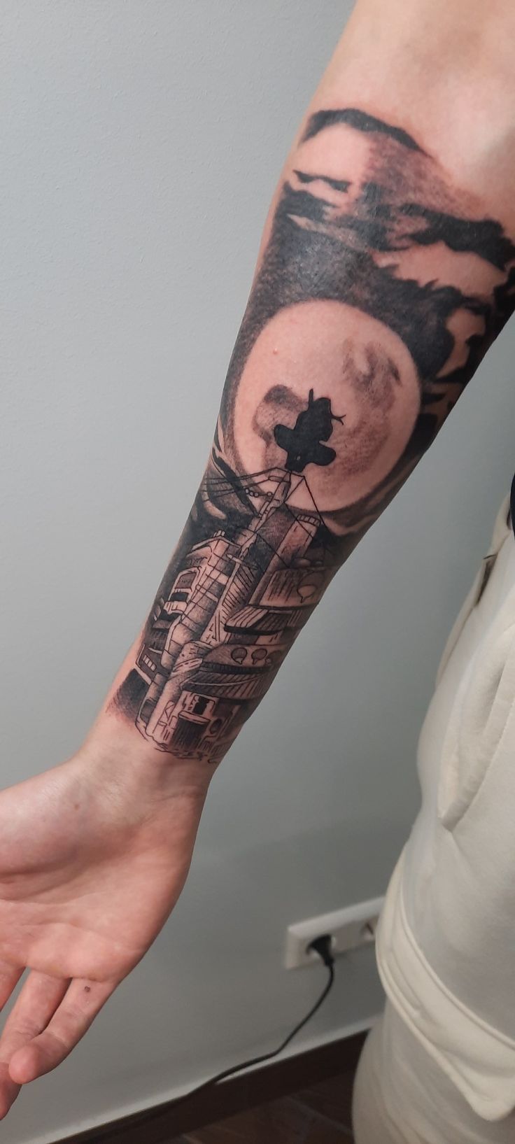 a person with a tattoo on their arm and the moon in the sky behind them