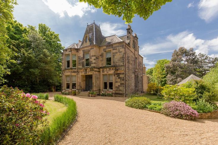 a large stone building surrounded by trees and flowers