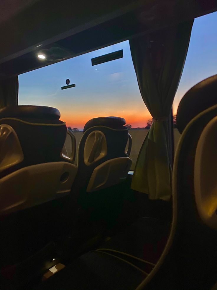 the sun is setting in the distance as seen from inside a bus with no passengers