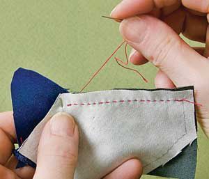 two hands are working on an origami piece with scissors and thread in it