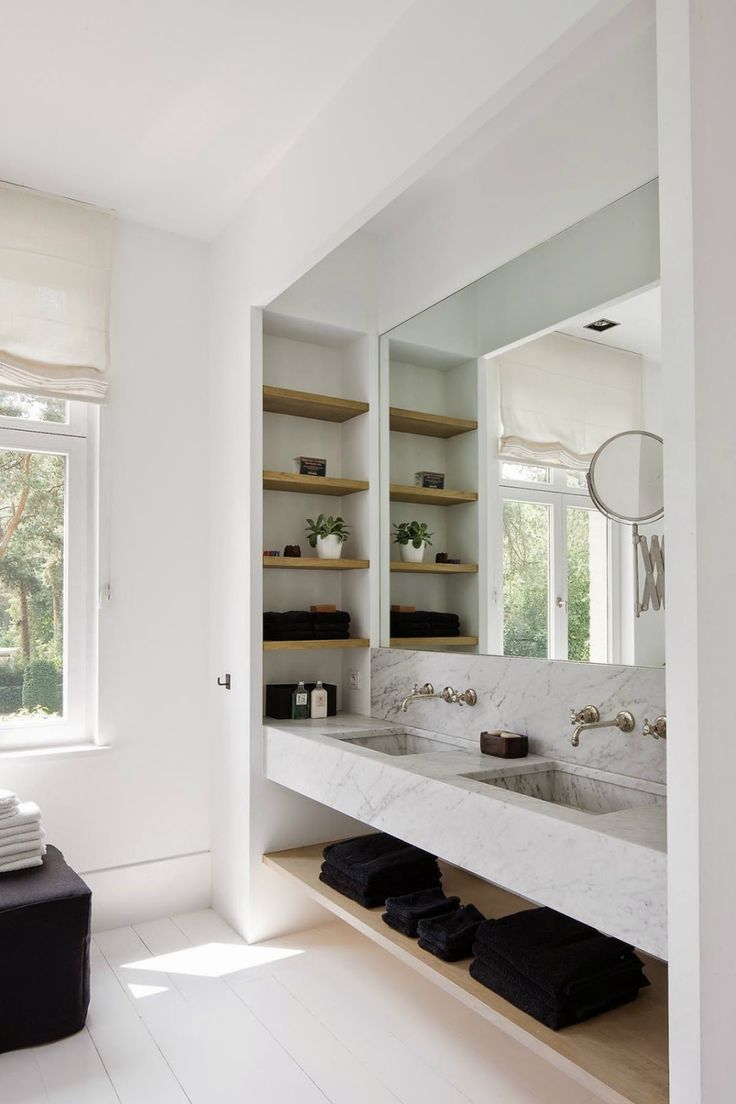 an image of a bathroom setting with white walls and flooring, including open shelving