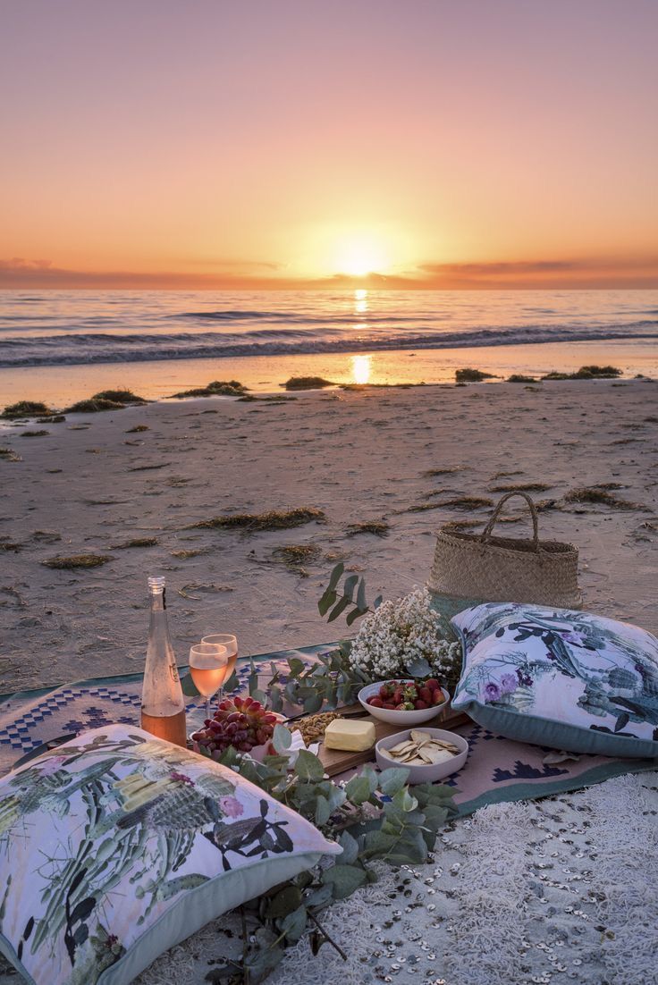 a picnic is set up on the beach at sunset