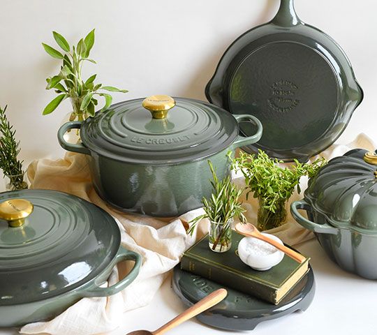 green pots and pans with plants in them on a white tableclothed cloth