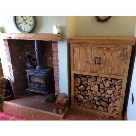 a wood burning stove in a living room next to a firewood log rack and clock