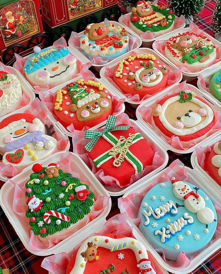 many decorated christmas cookies in plastic containers on a table