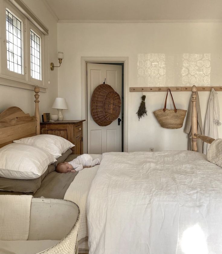 a bed with white sheets and pillows in a bedroom next to a wooden headboard