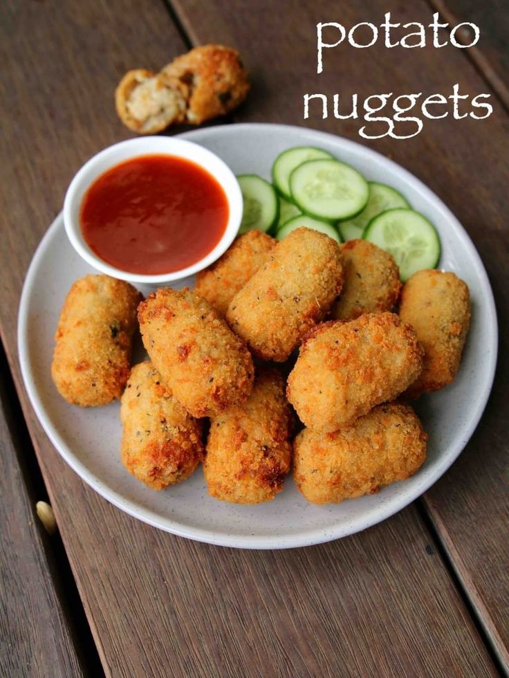 a white plate topped with cucumbers and tater tots next to a bowl of ketchup