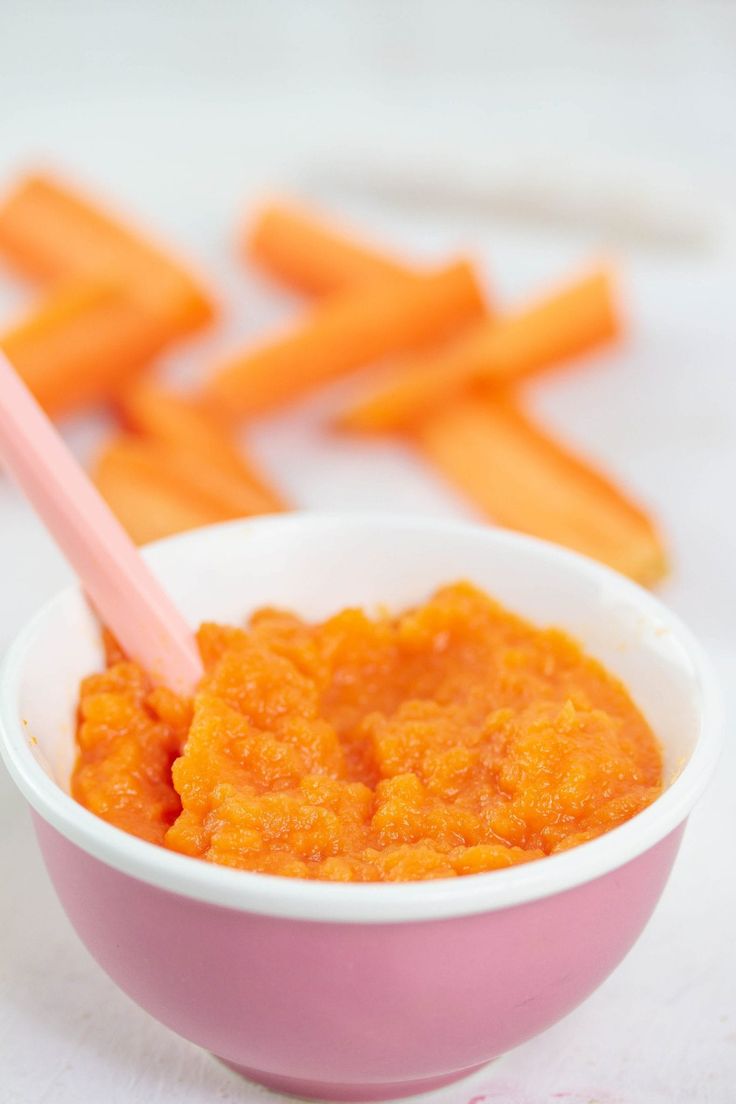 a bowl filled with carrots next to cut up sticks