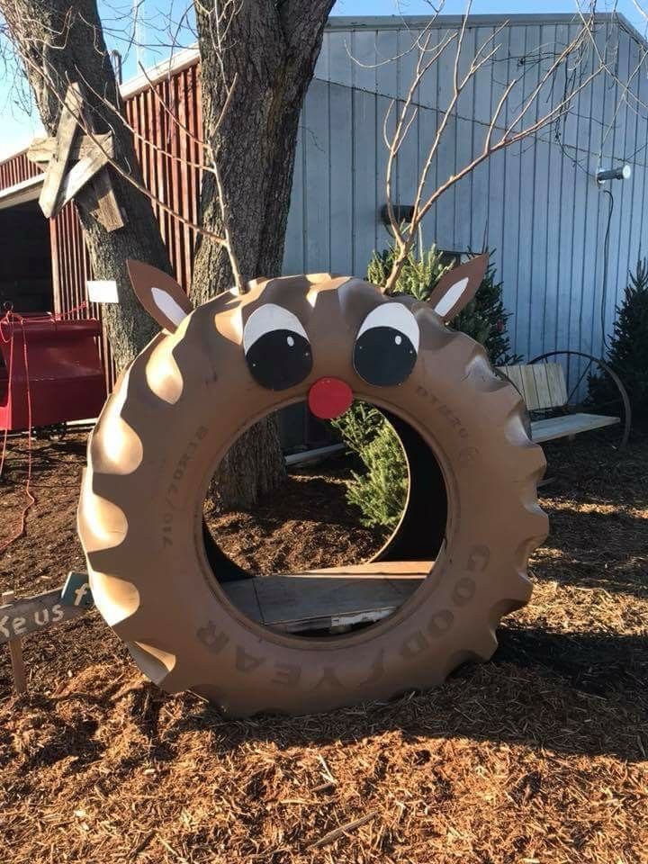 an inflatable tire with eyes and nose on the ground next to a tree