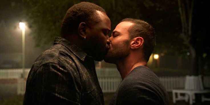 two men kissing each other in the dark