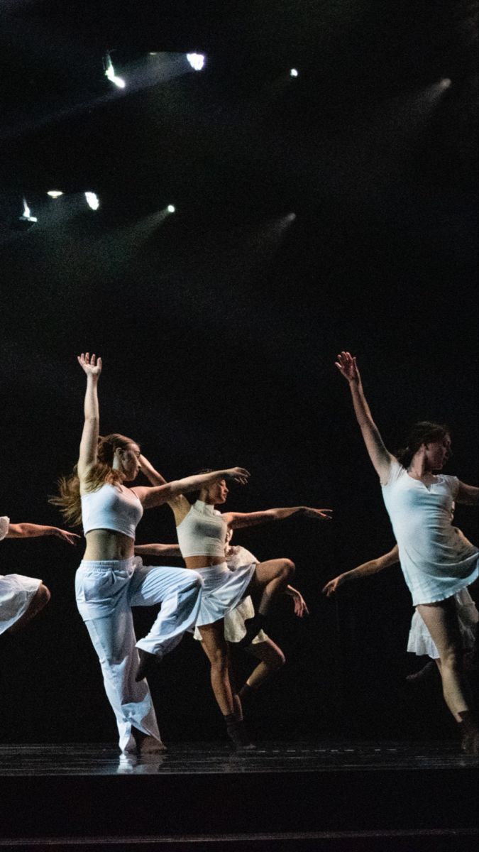 dancers in white are performing on stage with their arms up and legs spread out to the side