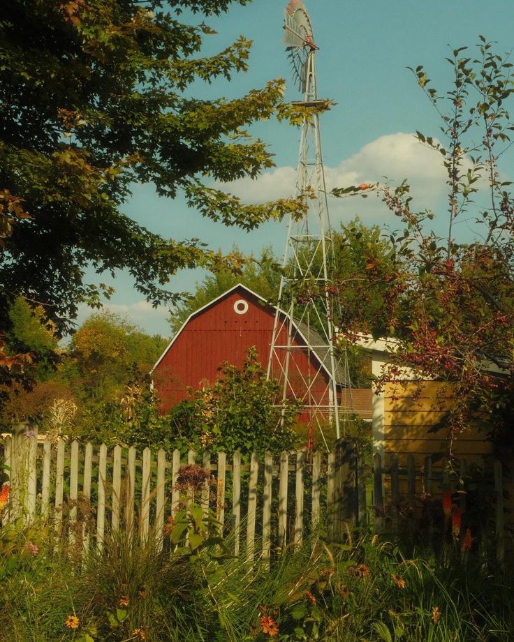 a red barn with a windmill in the background