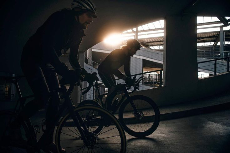 two bicyclists riding in the dark at night