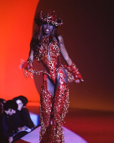 a woman is walking down the runway in a red dress with sequins on it