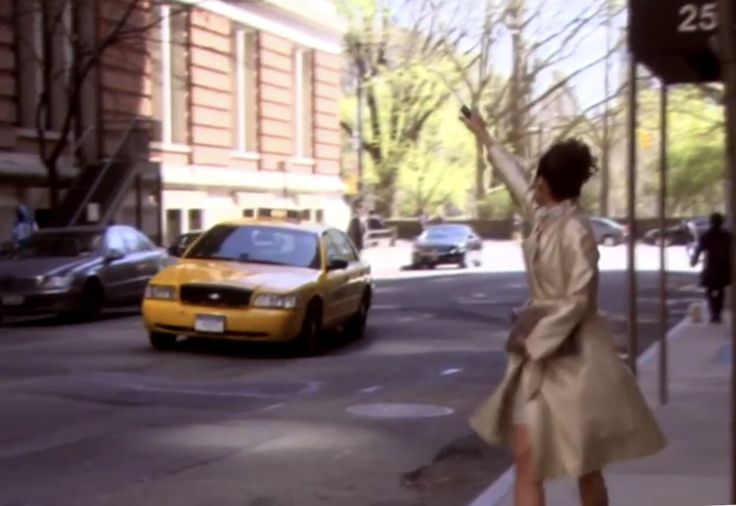 a woman standing on the side of a street next to a yellow taxi cab in front of a tall building