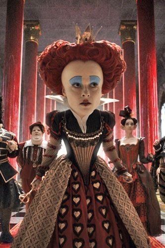 an animated image of a woman with red hair and blue eyes, surrounded by other dolls