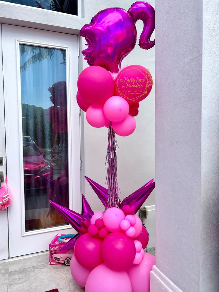 pink balloons and other decorations are on the ground in front of a door with an entrance