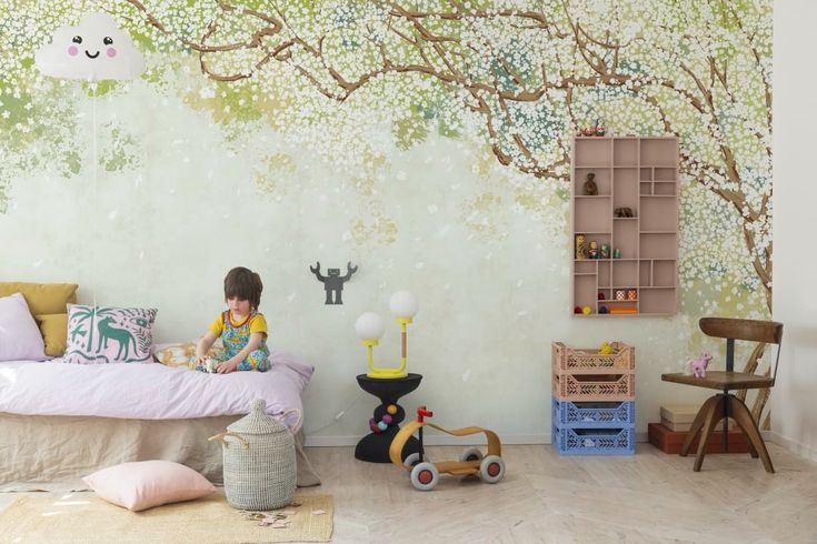 a child sitting on a bed in front of a tree mural