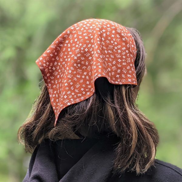 a woman with long hair wearing a bandana on her head and looking off into the distance