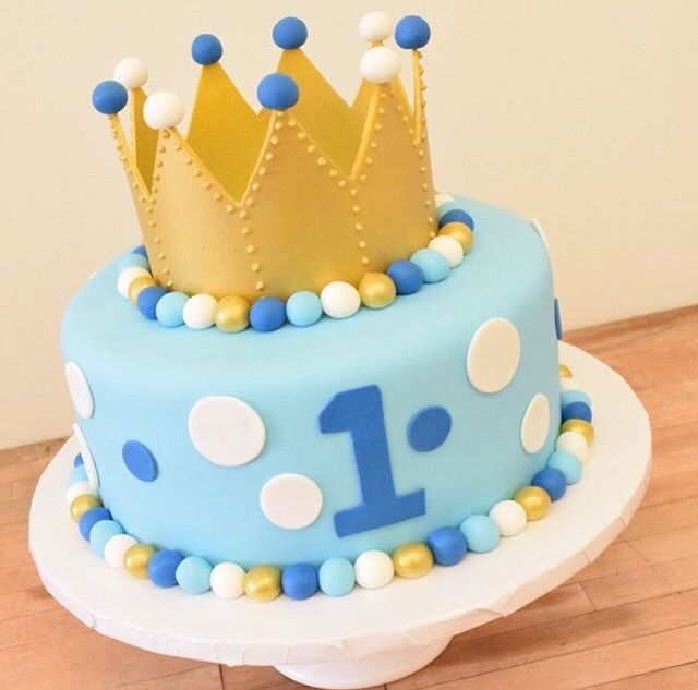 a birthday cake decorated with blue and gold frosting, polka dots and a crown on top