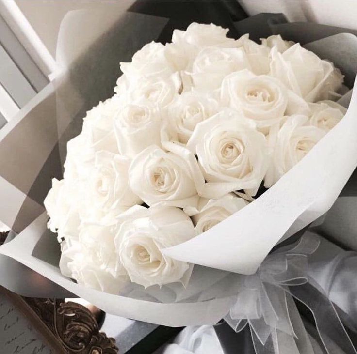 a bouquet of white roses sitting on top of a table