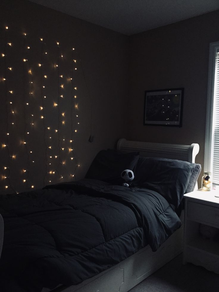 a bedroom with lights on the wall and a bed in front of a large window