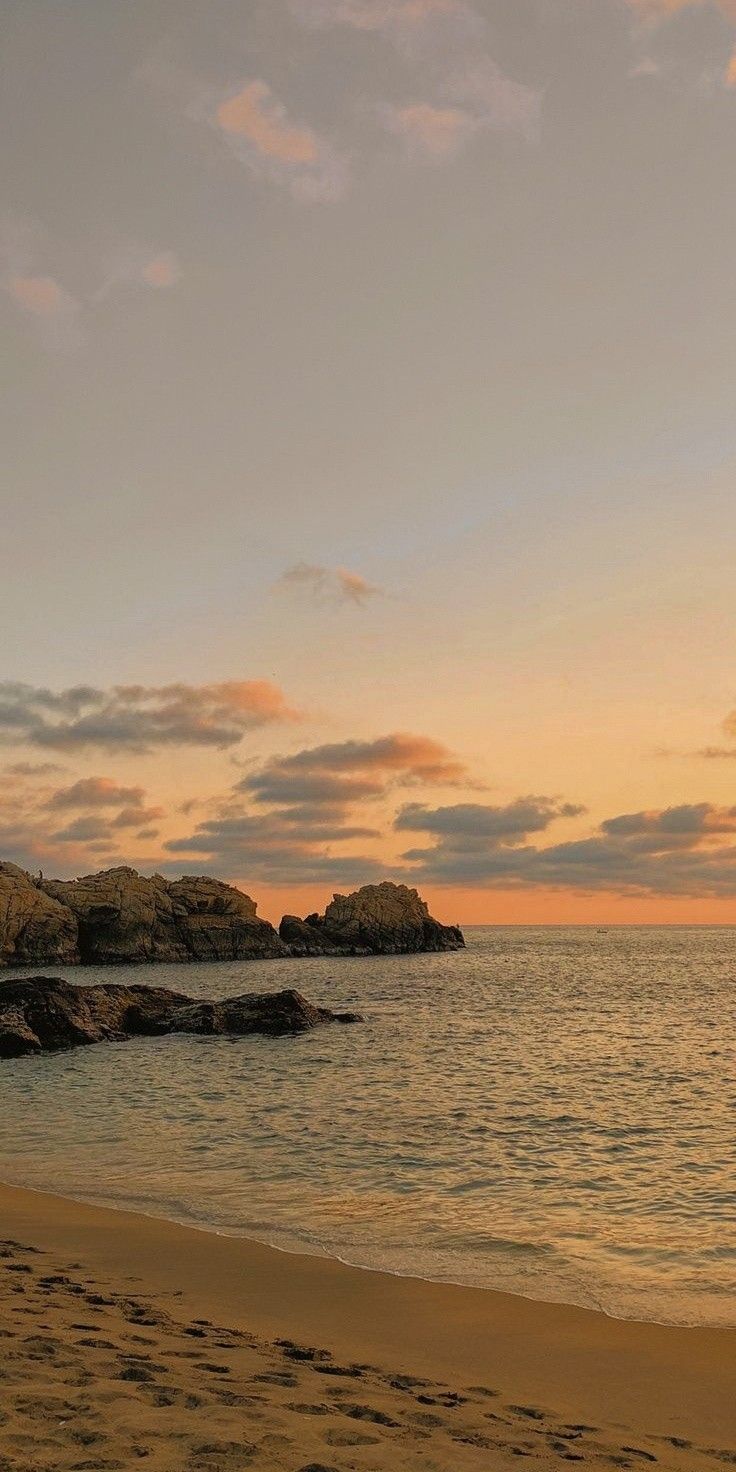 a person walking on the beach at sunset