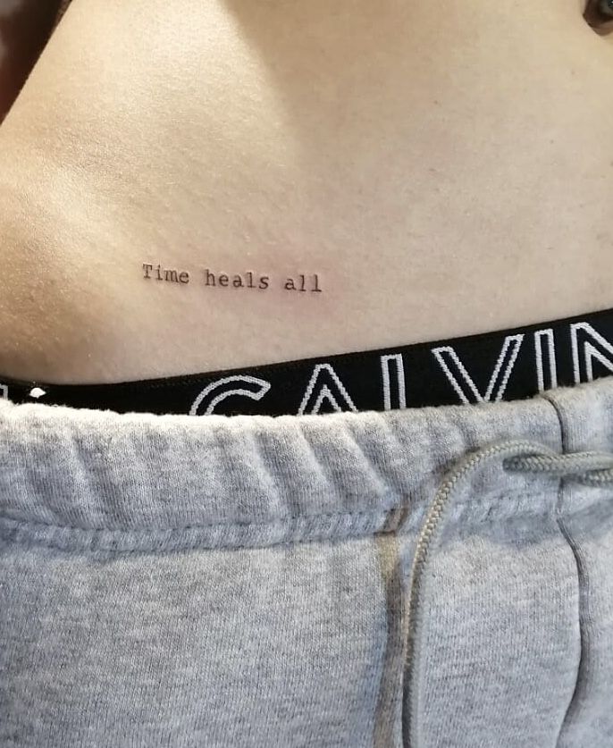 the back of a woman's stomach with an inscription on it that says time heals all