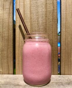 a pink smoothie in a mason jar with two straws