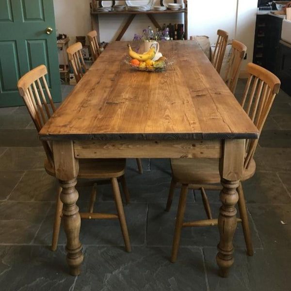 a wooden table with chairs around it in a kitchen next to a green door and shelves