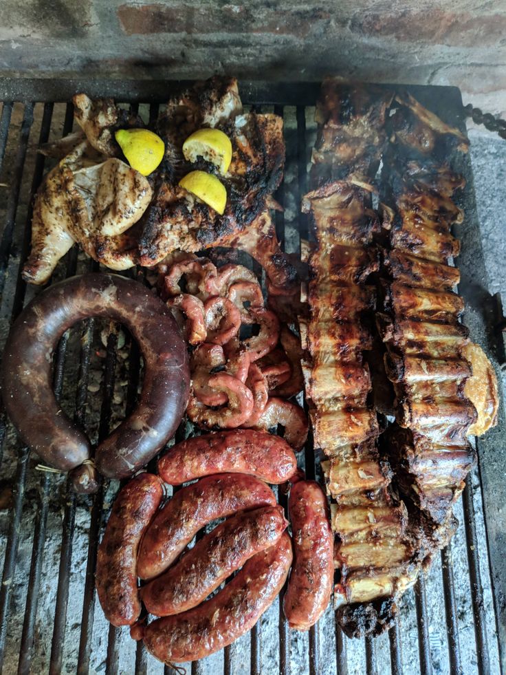 sausages, bratwurst and other meats cooking on a bbq grill