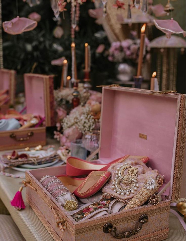 an open suitcase sitting on top of a table filled with shoes and other items next to candles